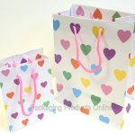 Two white gift bag with handles, printed with lots pastel coloured hearts